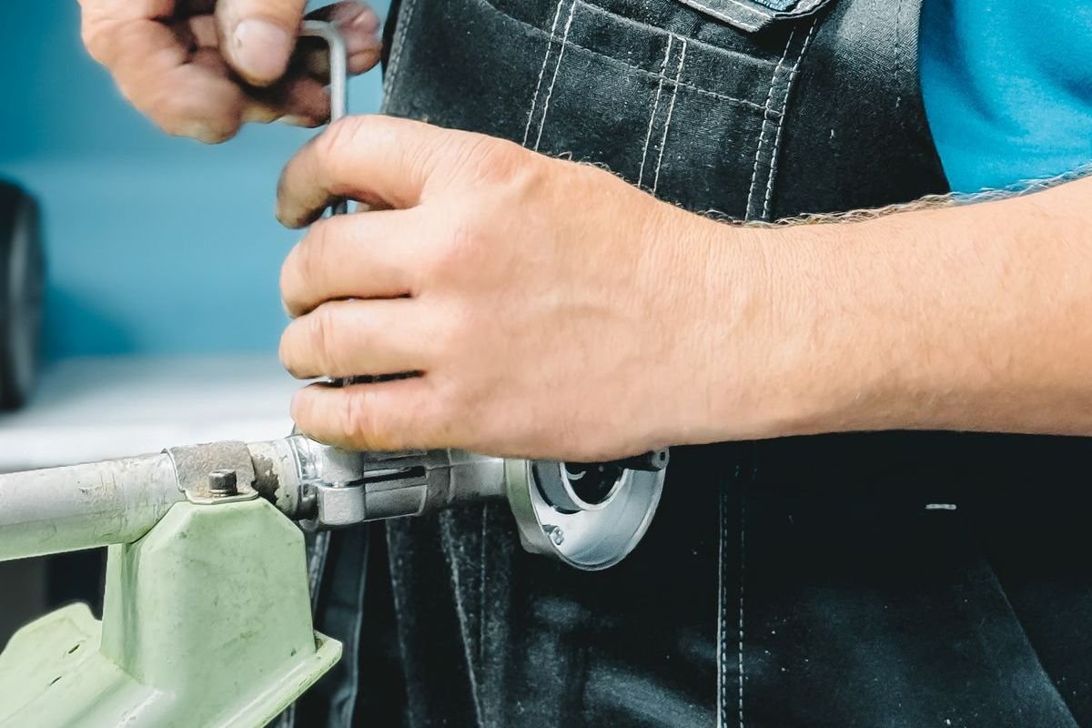 Plumber in work overalls tightening a pipe fitting with a hex key